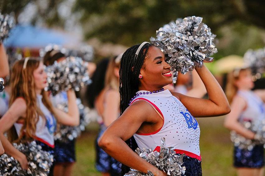 Cheerleader smiles while raising her pompoms 