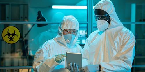 Two people working in a lab with safety suits on.